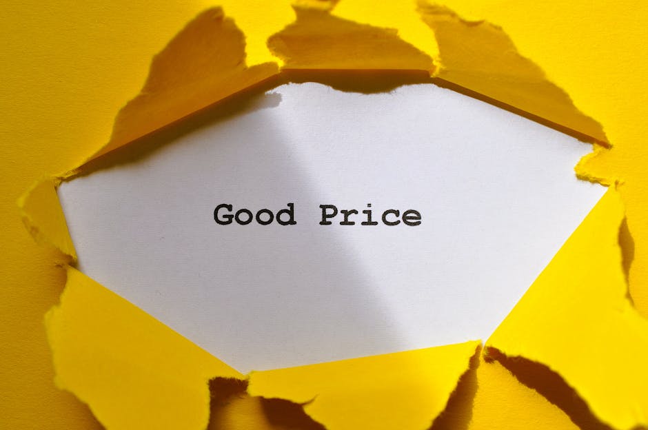 A close-up of a torn yellow paper surface revealing a white inner layer with the words 'Good Price' printed in black, symbolising transparent and affordable house removals. The torn edges of the yellow paper create an irregular frame around the central message, which is placed on a flat surface. This visual could relate to the process of packing, unpacking, or quoting for furniture transport and home relocation services. The presence of the torn packaging material emphasizes careful handling and efficiency, aligning with the services offered by Man with Van Bow in the removals category. The lighting highlights the texture of the torn paper, and the overall composition suggests a focus on clear, upfront pricing, supporting the topic of house removals prices explained on the webpage.